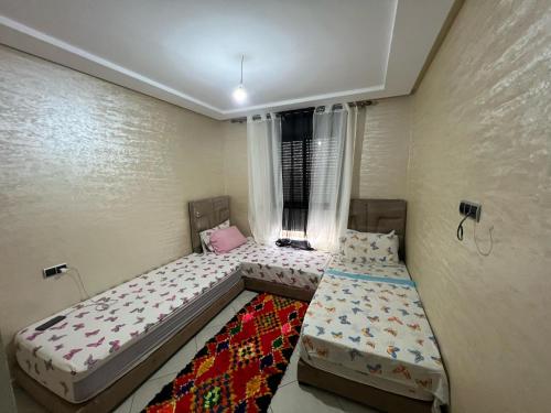 ein Schlafzimmer mit zwei Betten und einem Teppich in der Unterkunft Résidence les belles Rives in Bouznika