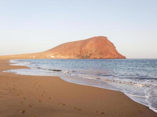 a sandy beach with a mountain in the ocean at Trip Medano England Centro in El Médano