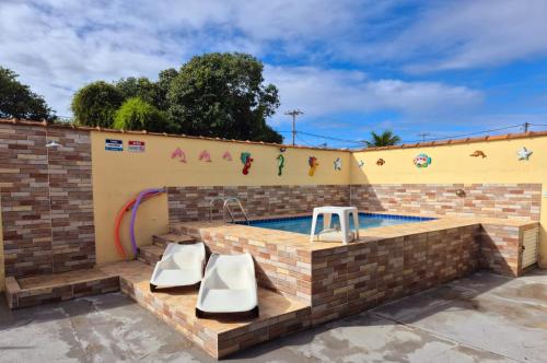 a backyard swimming pool with a brick wall and two white slides at Casa em Condomínio com Piscina Privativa in Araruama