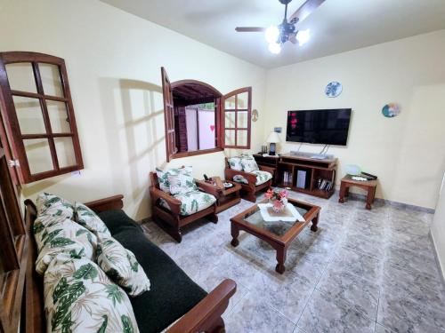 a living room with a couch and a tv at Casa em Condomínio com Piscina Privativa in Araruama