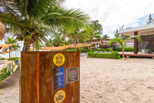 a sign on the beach with palm trees in the background at Casa Jaguar in Xpu Ha