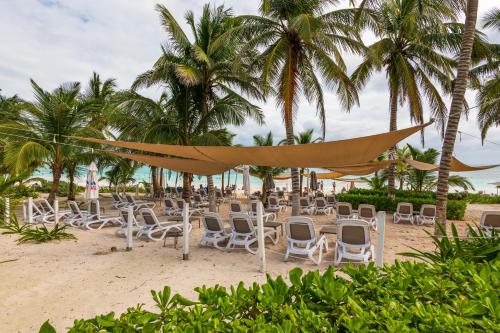 a beach with chairs and umbrellas and palm trees at Casa Jaguar in Xpu Ha