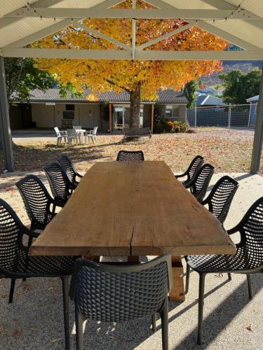 a wooden table with chairs under an umbrella at Willow Dene Holiday Apartments in Bright
