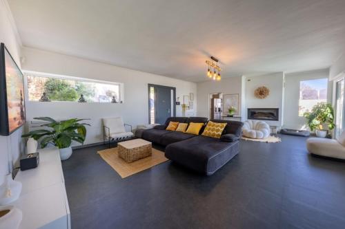 un salon avec un canapé noir et une table dans l'établissement 06 Bl - Superb contemporary villa with sea view, à Villeneuve-Loubet