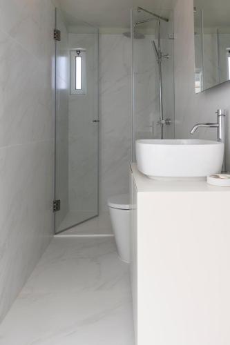 a white bathroom with a sink and a shower at Prainha Residences-A17 -Portimão in Alvor