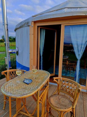 a table and two chairs with wine glasses on a deck at Glamping Niebiańska Osada Jurty Dolnośląskie & SPA in Polanica-Zdrój
