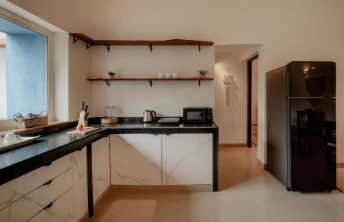 a kitchen with a black counter top and a refrigerator at CasaKai 2BHK Bohemian Spread with 3 Patios & Pool, Near Thalassa in Siolim