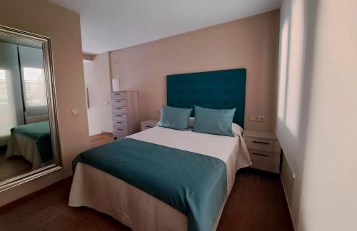 a bedroom with a large bed with a blue headboard at Apartamento La Monina CUEVAS DEL VALLE in Cuevas del Valle