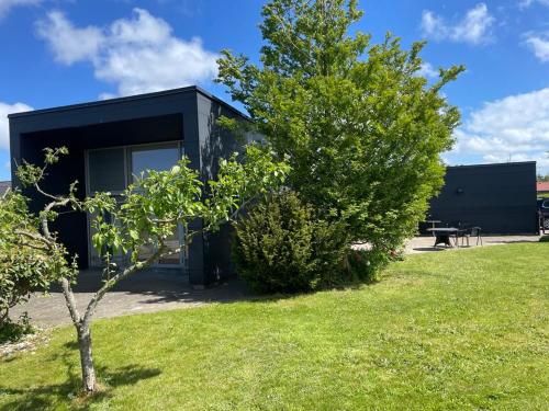 a black house with a tree in the yard at Spangkærparken 53 in Hjørring