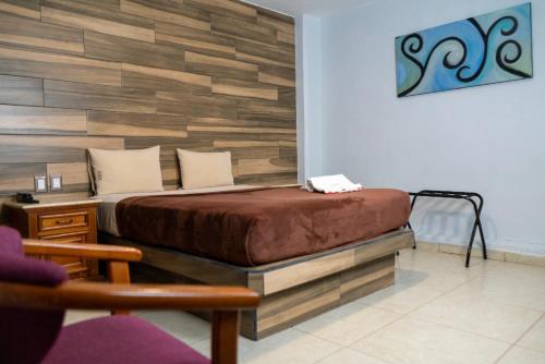 a bedroom with a bed with a wooden wall at Hotel Santiago De Compostela - Guadalajara Centro Historico in Guadalajara