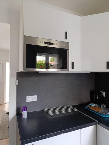 une cuisine avec des armoires blanches et un comptoir noir dans l'établissement Jolie petite maison à Paris, à Villejuif