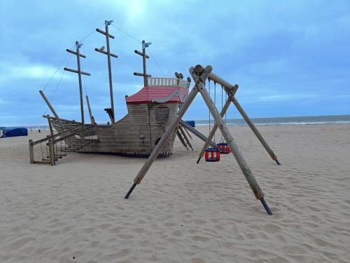 a swing set on a beach with a boat at Sun and Sea De Haan in De Haan