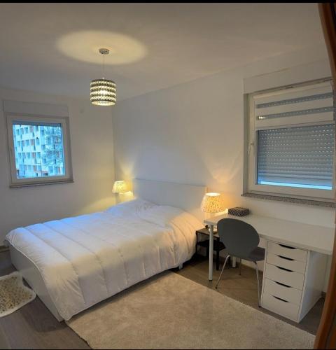 - une chambre avec un lit blanc, un bureau et une fenêtre dans l'établissement Logement des jours heureux, à Mundolsheim