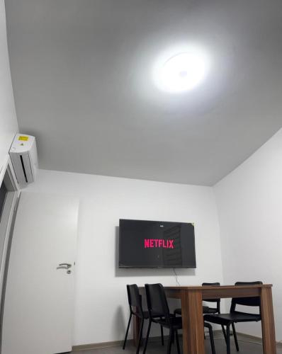 une table avec des chaises et une télévision murale. dans l'établissement Logement des jours heureux, à Mundolsheim