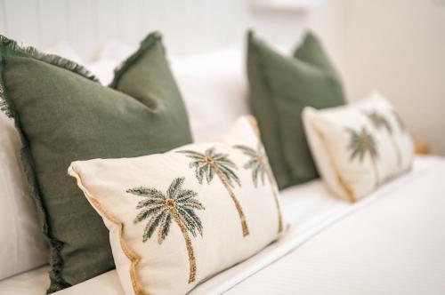 a white couch with green pillows with palm trees on it at Essence Peregian Beach in Peregian Beach