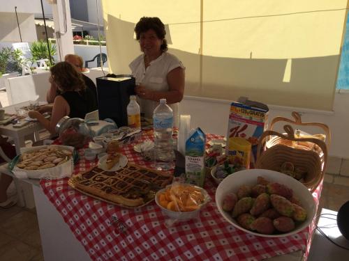 een vrouw die voor een tafel staat met eten bij B&B Cuore di Gallipoli in Gallipoli