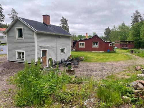 a white house and a red house with a yard at Lilla Skogsnära in Kolmården
