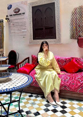 a woman in a yellow dress sitting on a couch at Le panoramique de Fes in Fès