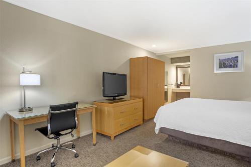 a hotel room with a bed and a desk and a tv at Best Western Plus Dixon Davis in Dixon