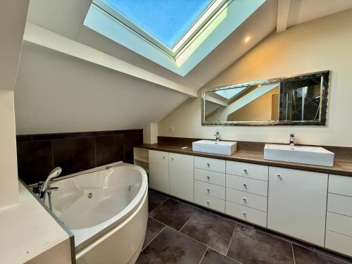 a bathroom with two sinks and a tub and a skylight at Le Jardin de Rose et Capucine, piscine et jardin avec terrasse in Gérardmer