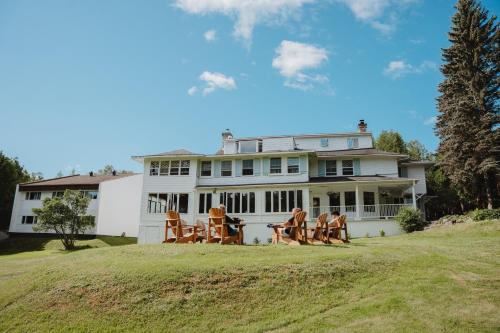 a group of people sitting on a lawn in front of a house at Auberge Les Sources in La Malbaie