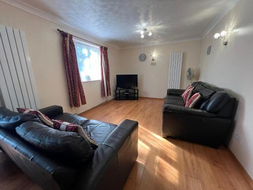 a living room with two leather couches and a television at Spacious 4 bed Farnborough AirShow in Farnborough