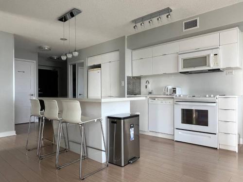 a kitchen with white appliances and bar stools at The Signature at CityPlace in Toronto