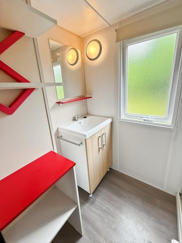 une petite salle de bain avec un lavabo et une fenêtre dans l'établissement Mobil-home Le Sorbier, 6pers, à Saint-Pantaléon-de-Lapleau