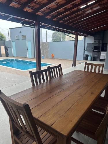 a wooden table with four chairs and a pool at Casa de Lazer com piscina in Pirassununga