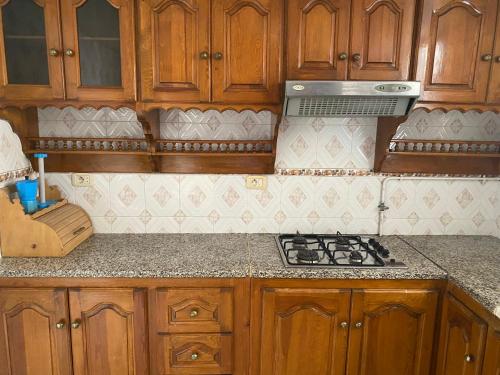 Una cocina con gabinetes de madera y un horno de estufa. en Cosy S3 a sousse, en Bin Rhilouf