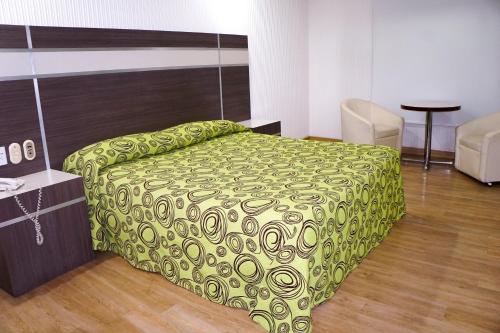 a bedroom with a bed with a green comforter at Hotel Castillo in Mexico City
