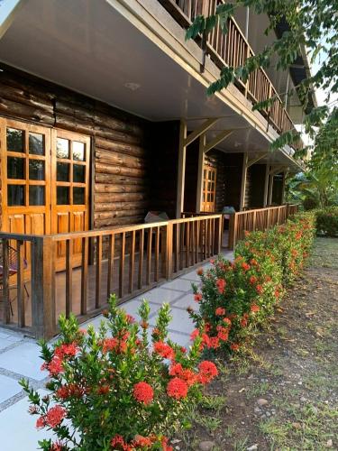 a porch of a log cabin with red flowers at Hotel Luna Azul Tatacoa in Villavieja