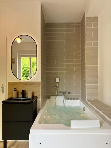 La salle de bains est pourvue d'une baignoire avec un lavabo et un miroir. dans l'établissement Évasion spa près de Giverny, à Vernon
