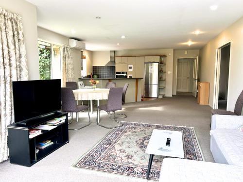 a living room with a couch and a table at Sunny Garden Retreat - 3-BR Home near Mall, City & Airport in Christchurch