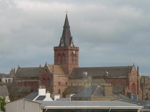 a large brick building with a clock tower at Ayre Hotel & Ayre Apartments in Kirkwall