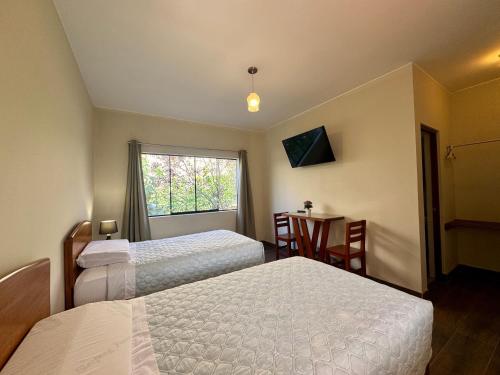 a bedroom with two beds and a table and a window at Casa Hotel Mamaluna in Lunahuaná