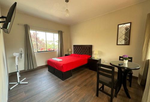 a bedroom with a red bed and a table at Casa Hotel Mamaluna in Lunahuaná
