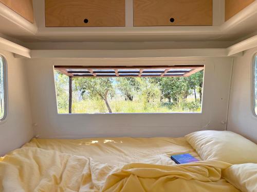 a bed in a small room with a window at Chic vintage caravan retreat, just 25 mins to the beach in Odeceixe