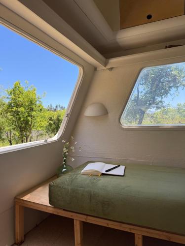 a bedroom with a bed and two windows at Chic vintage caravan retreat, just 25 mins to the beach in Odeceixe