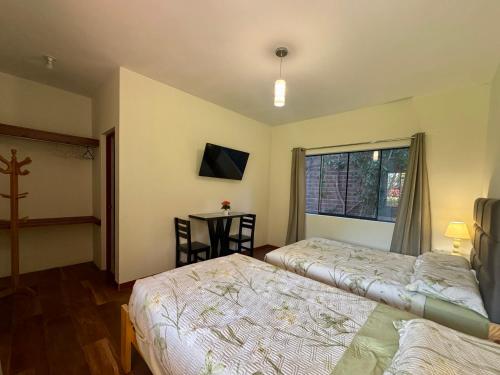 two beds in a room with a table and a window at Casa Hotel Mamaluna in Lunahuaná