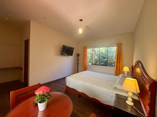 a bedroom with a bed and a table and a window at Casa Hotel Mamaluna in Lunahuaná