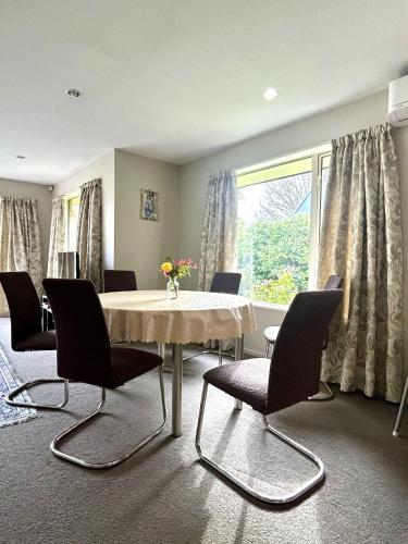 a dining room with a table and chairs and a window at Sunny Garden Retreat - 3-BR Home near Mall, City & Airport in Christchurch