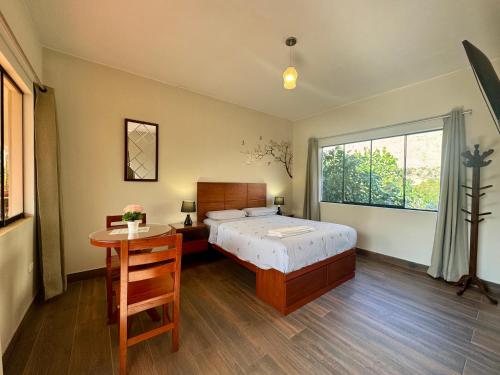 a bedroom with a bed and a table and a window at Casa Hotel Mamaluna in Lunahuaná