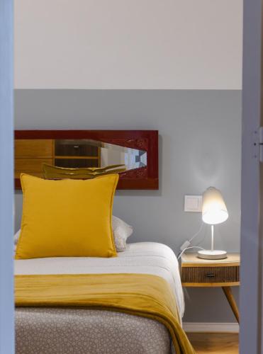 a bed with a yellow pillow and a lamp on a table at BABhouse Casa da Colmeia - Coração do Douro in São João da Pesqueira