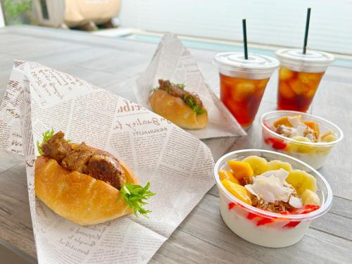 ein Tisch mit einem Sandwich und einem Salat und Getränken in der Unterkunft Naminoma Blue 青島 in Miyazaki