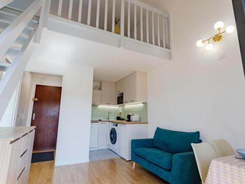 un salon avec un canapé bleu et une cuisine dans l'établissement Apartment Deauville Plage 1 et 2-27 by Interhome, à Villers-sur-Mer