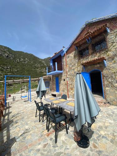 a table with chairs and umbrellas on a patio at Casa Tissemlal in Chefchaouene