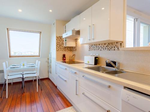 une cuisine avec des armoires blanches, une table et une fenêtre dans l'établissement Apartment Cap Cabourg-33 by Interhome, à Cabourg