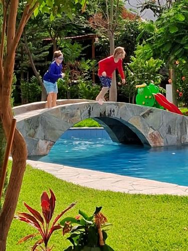two children jumping on a bridge over a pool at Casa Hotel Mamaluna in Lunahuaná