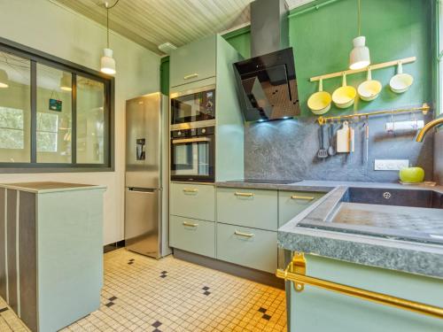 - une cuisine avec des murs verts et des placards blancs dans l'établissement Holiday Home La Sablière by Interhome, à Lanton